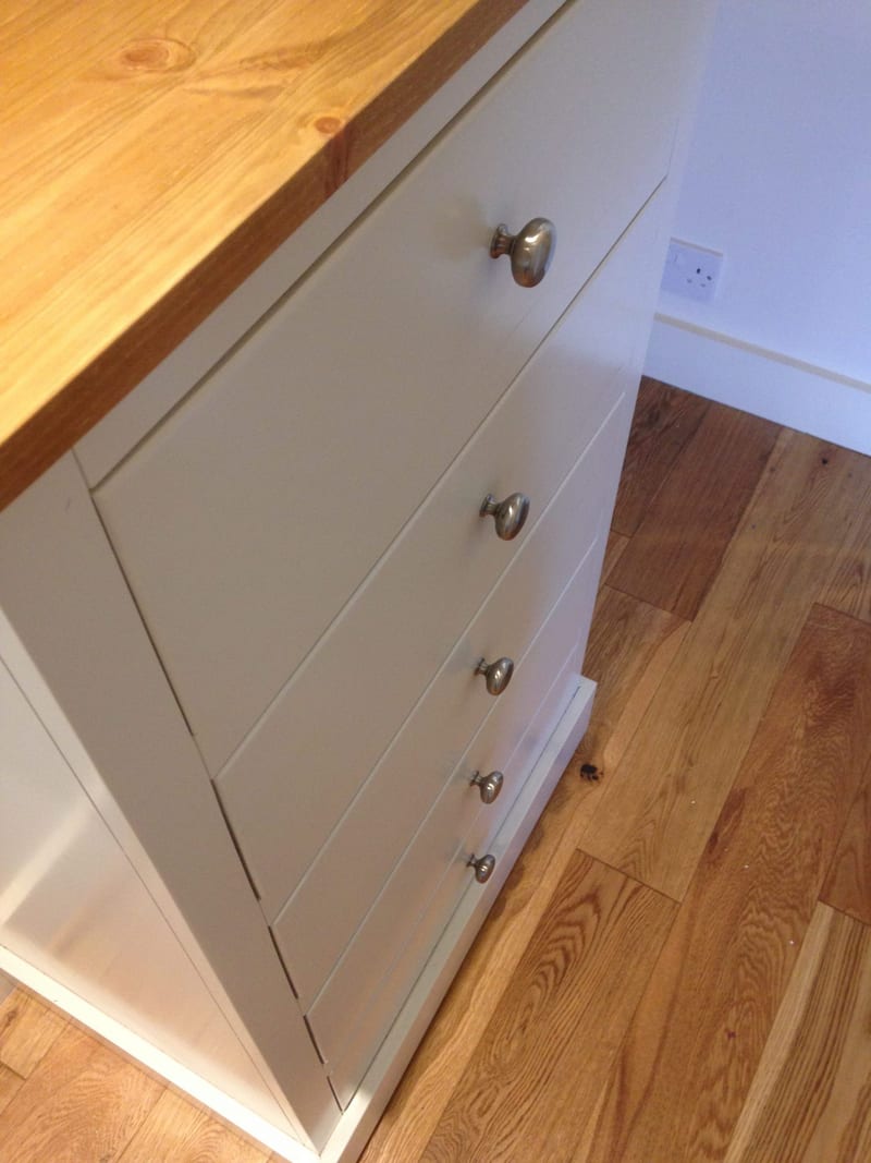 Angled overhead view of a companion Harlington drawer unit, showing five graduated drawers with brushed nickel knobs beneath a solid timber top on an oak floor