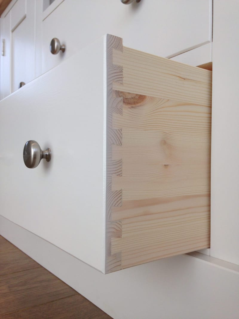 Detail of a drawer pulled fully out of the painted TV cabinet, showing the hand-cut dovetail joints and natural solid pine drawer box construction