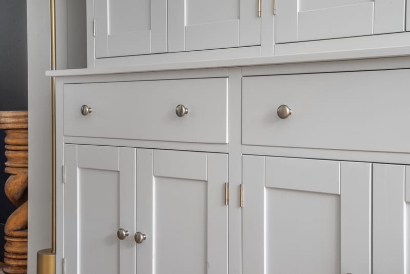 Close view of the dresser base showing two wide drawers with brushed nickel knobs above Shaker panelled cupboard doors, with slim brass edge pulls between them
