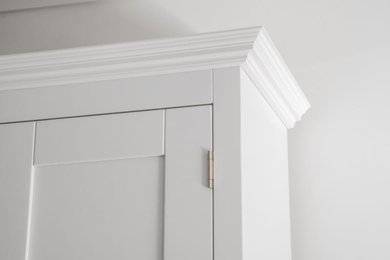 Detail of the top corner of the Welsh dresser, showing the stepped white cornice moulding and a brass butt hinge set into the panelled door