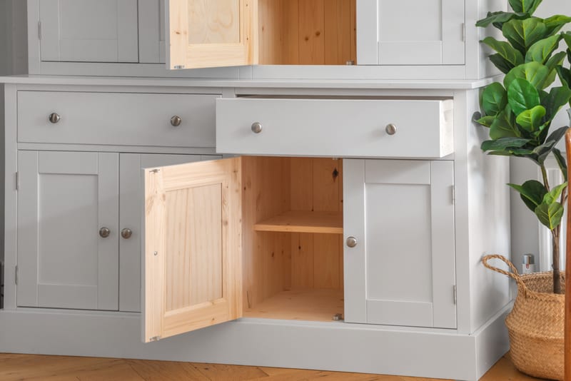 The Radwell dresser with an upper door, a base cupboard door and a drawer all standing open, revealing the natural solid pine interiors, an adjustable shelf and tongue-and-groove pine back panels behind the grey painted carcass