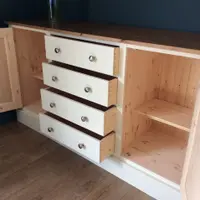 Both cupboard doors open and all four drawers pulled out, showing the natural pine drawer boxes with dovetailed corners, the bare pine interior and an adjustable shelf in the right cupboard