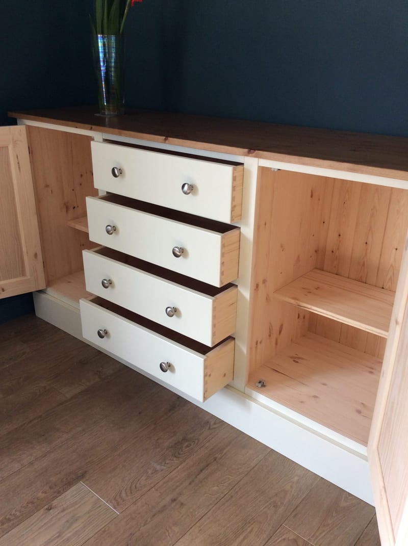 Both cupboard doors open and all four drawers pulled out, showing the natural pine drawer boxes with dovetailed corners, the bare pine interior and an adjustable shelf in the right cupboard