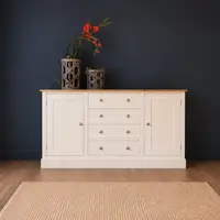 Cream painted 5ft sideboard with a solid oak top and four cup handled drawers between two shaker doors, against a dark navy wall with woven lanterns and red gladioli on top