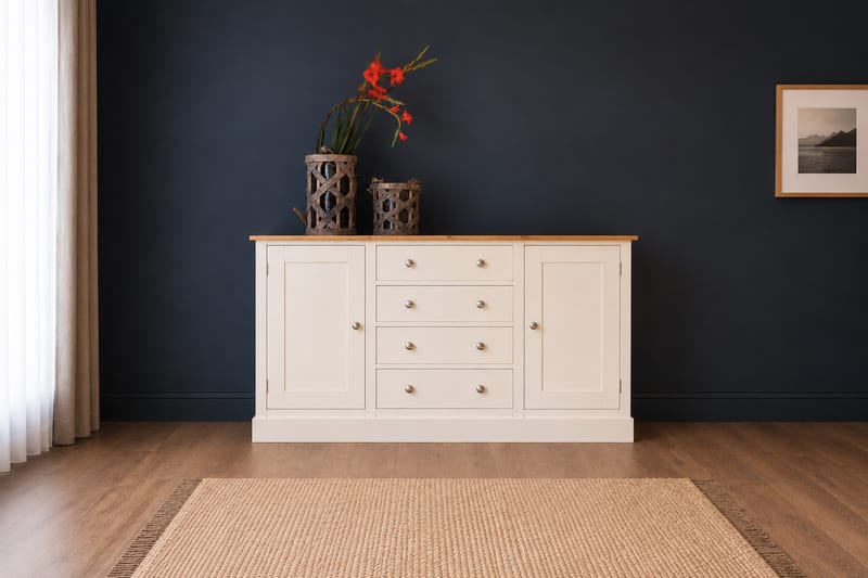 Cream painted 5ft sideboard with a solid oak top and four cup handled drawers between two shaker doors, against a dark navy wall with woven lanterns and red gladioli on top