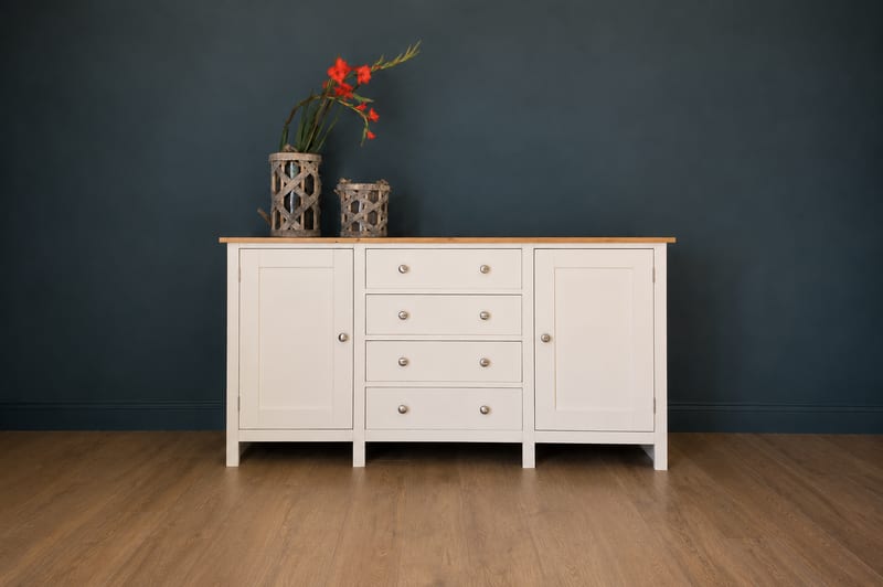 Cream painted 5ft sideboard on square legs with a solid oak top, four cup handled drawers between two shaker doors, against a dark blue wall with woven lanterns and red gladioli