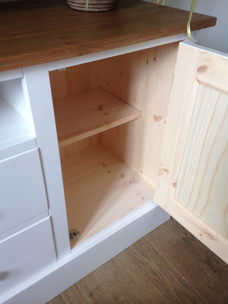 Cupboard door opened on the white painted unit, showing the bare pine interior with a single shelf, the boarded pine back and the unpainted inner face of the panelled door
