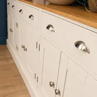 Close angled view of the sideboard front, showing the brushed nickel cup handles on the drawers, the round knobs on the shaker doors and the oak top with a stone bowl resting on it