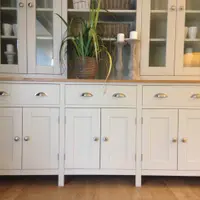 Close view of the dresser base, showing the waxed pine top, three drawers with brushed nickel cup handles, six shaker doors with round knobs and the glazed rack starting above