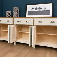 View of the sideboard with all six doors open, revealing natural pine interiors with tongue-and-groove backs and a shelf in each bay, the three drawers closed with nickel cup handles above