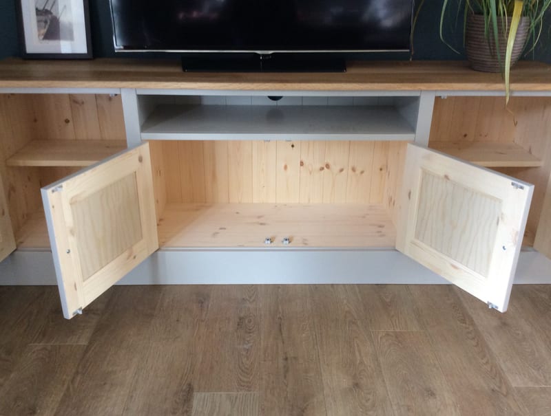 View of the media unit with the two central doors open, revealing a natural pine interior with tongue-and-groove back, a painted shelf above and the television and plant on the oak top