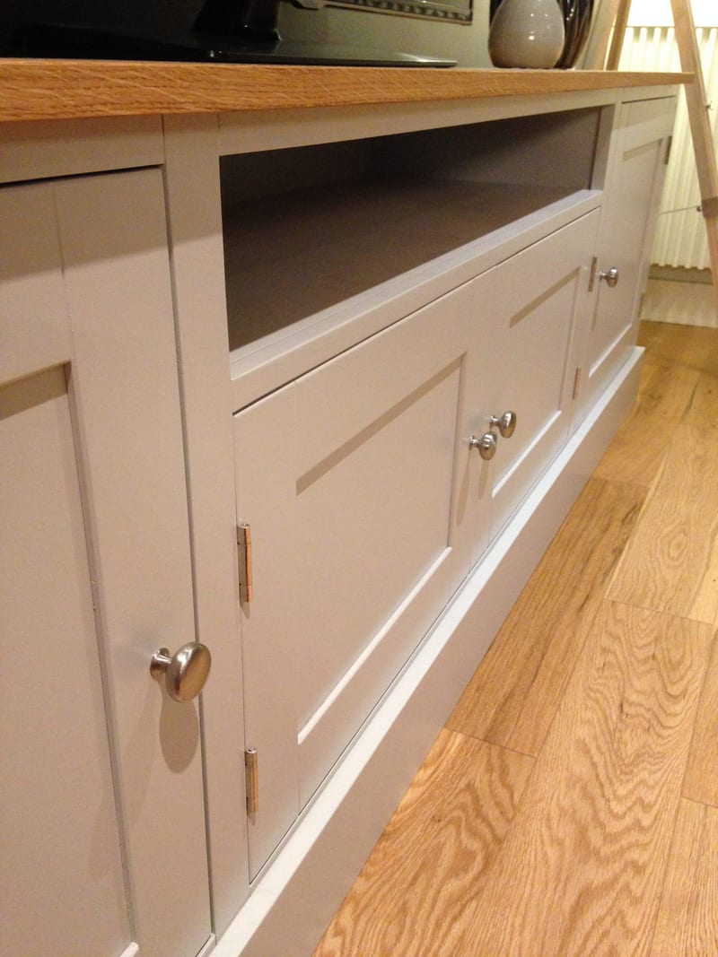 Angled view of the centre of the unit, showing the open media shelf with its painted lining, the two doors below on brushed nickel knobs and brass hinges beneath the oak top