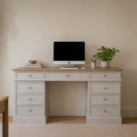 Grey painted pedestal desk with a solid oak top and nine drawers, an iMac, books and a plant on top, with a boucle chair and a jute rug in a pale room