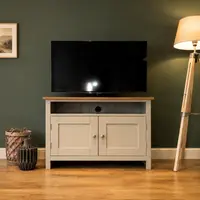 Cream painted 3ft shaker style TV cabinet with a solid oak top, an open media shelf and two cupboard doors, with a television on top against a deep green wall
