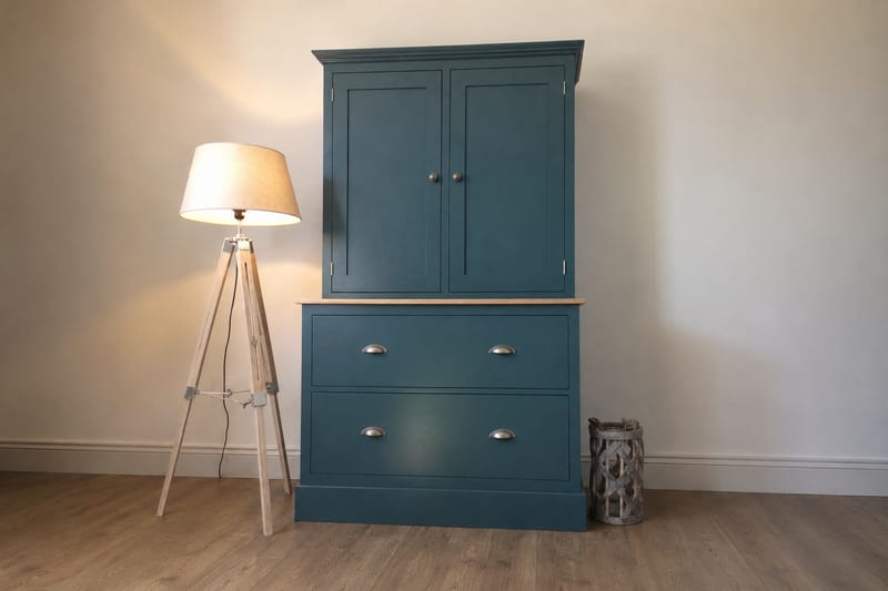 Teal painted dresser with two shaker doors above a solid oak top and two deep cup handled drawers, standing beside a wooden tripod floor lamp
