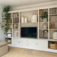 Wide view of the off-white media wall in a living room, with open shelving around the television, panelled base cupboards, seagrass baskets in the end recesses and a jute rug underfoot