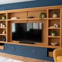 Front view of the 10ft Woburn media unit against a navy wall, with a navy painted cupboard base, oak open shelving either side of a large television and an oak veneer backboard