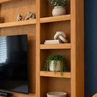 Detail of the right-hand oak bookcase, its adjustable shelves holding a eucalyptus vase, a knot ornament on books, a trailing plant and a stone bowl