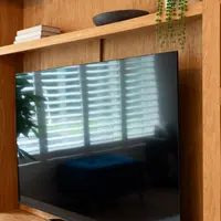 Close view of the oak veneer backboard behind the television, with the central shelf above and open shelving either side