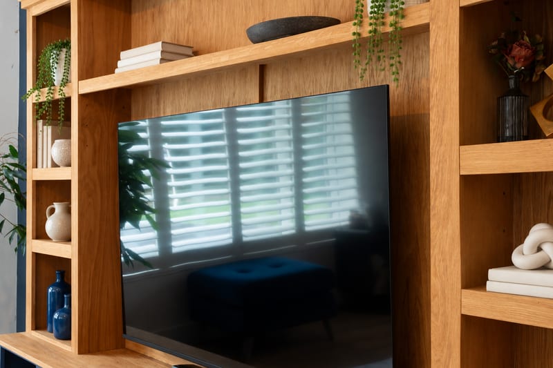 Close view of the oak veneer backboard behind the television, with the central shelf above and open shelving either side