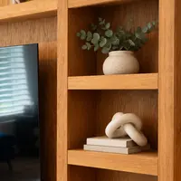 Close-up of the oak shelving joinery and grain, with a eucalyptus stem in a stoneware vase and a ceramic knot ornament resting on books