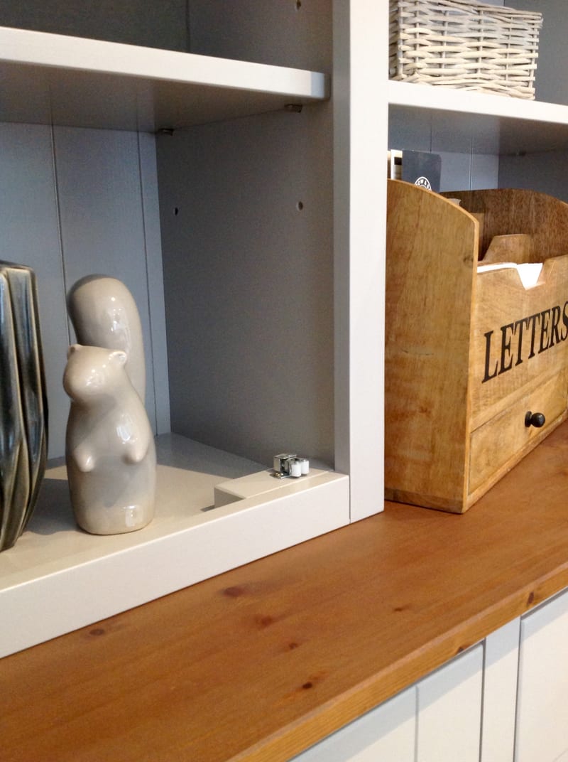 Close view of the open shelving above the timber top, showing painted shelves, a grey tongue-and-groove back, two ceramic animal figures, a wicker basket and a wooden letters box