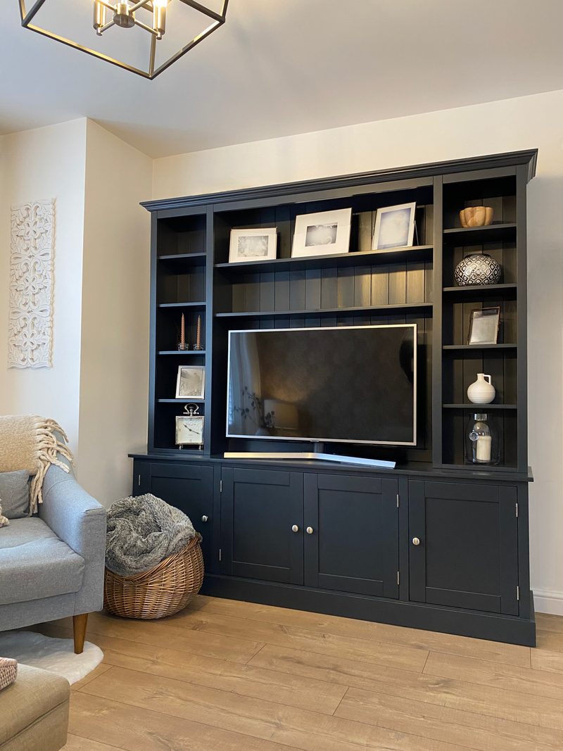 Charcoal painted 6ft Radwell media unit with a television between tall open shelves holding framed prints and ceramics, and four cupboard doors below, beside a grey armchair