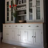 Angled view from the left of the off-white painted dresser, showing the oiled timber top, three drawers with brushed nickel cup handles and six panelled cupboard doors with round knobs