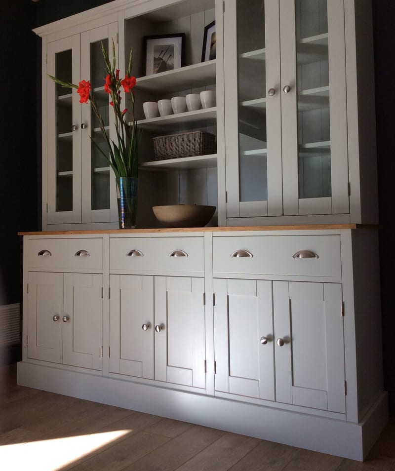 Angled view from the left of the off-white painted dresser, showing the oiled timber top, three drawers with brushed nickel cup handles and six panelled cupboard doors with round knobs