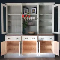 Full front view with every door open, showing painted shelves against a tongue-and-groove back, three closed drawers with cup handles and bare pine cupboard interiors below