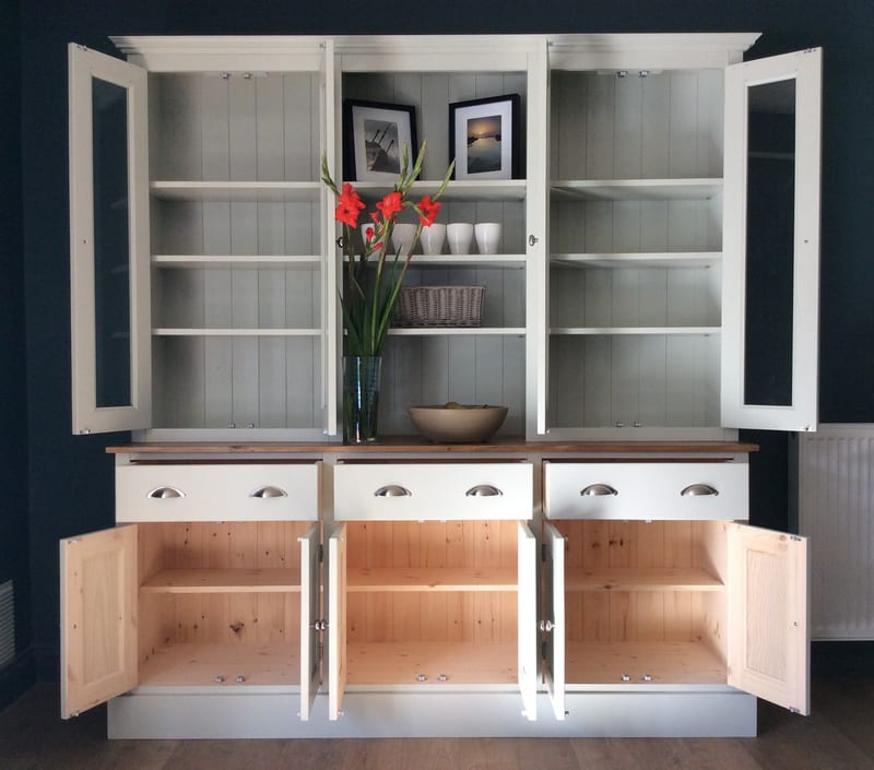 Full front view with every door open, showing painted shelves against a tongue-and-groove back, three closed drawers with cup handles and bare pine cupboard interiors below