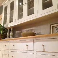 Upward view of the glazed top standing on the base, showing tongue-and-groove backing, two turned candlesticks and a stoneware bowl on the timber top with drawers below