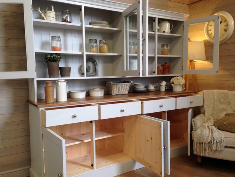 Full front view of the dresser with the glazed doors and lower cupboards open, revealing painted shelves above and natural pine interiors below, plus crockery and baskets on the worktop