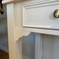 Close view of the corner of the white painted dressing table, showing the square leg, the shaped bracket beneath the apron and the moulded edge of the drawer front above