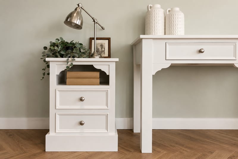 Cream painted Carlton large bedside cabinet with an open shelf above two drawers and shaped brackets, topped with a lamp, a framed photograph and a trailing plant
