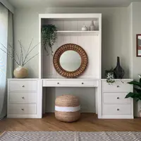 Straight-on view of the dressing table and shelved top between two matching three-drawer chests, with a jute pouffe beneath and a diamond-patterned rug across the wood floor