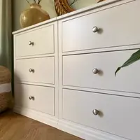 Close angled view across the drawer fronts, showing the two joined modules, the fine shadow gaps between the drawers, brushed nickel knobs and the moulded plinth at floor level