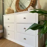 Angled view of the chest from its right-hand end, showing all six drawers, the join between the two modules and a top dressed with a gold vase, a ribbed white vase and a tall ridged jug