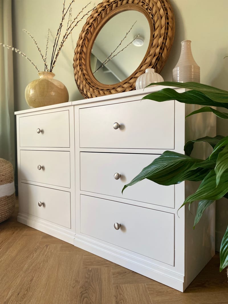 Angled view of the chest from its right-hand end, showing all six drawers, the join between the two modules and a top dressed with a gold vase, a ribbed white vase and a tall ridged jug