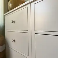 Tight close-up of the two chest modules meeting, showing the crisp painted edges, the recessed drawer fronts and three brushed nickel knobs on the left-hand bank