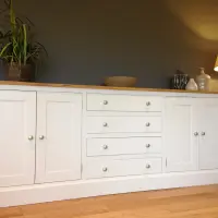 Cream painted 7ft Hinwick sideboard with a solid oak top, four central drawers flanked by two pairs of shaker doors, with a plant and a wooden bowl on top