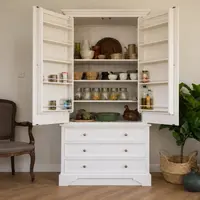 White painted larder cupboard with both doors opened to show spice racks on the doors and shelves of jars, bowls and baskets inside, above three deep drawers in the base