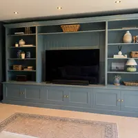 Wider view from the right with the dark blue-grey walls and ceiling spotlights, the patterned rug in the foreground and a black subwoofer standing beside the right-hand bookcase