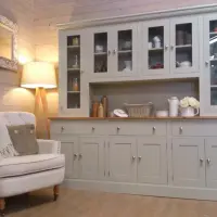 Sage grey painted 7ft Radwell Welsh dresser with glazed doors either side of a central open shelf, above an oak worktop, three drawers and cupboards, in a timber lined room