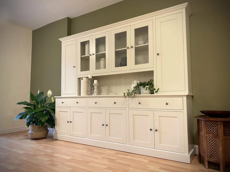Cream painted 8ft Radwell Welsh dresser with glazed centre doors flanked by tall solid doors, above an oak worktop with drawers and cupboards, against an olive green wall