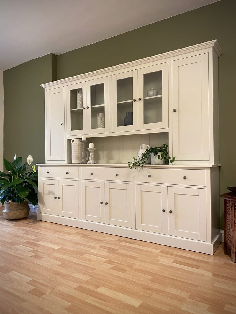 Full-height view from the right, showing the moulded cornice, glazed and solid upper doors, the painted worktop and the plinth base standing on pale wood-effect flooring