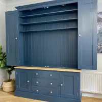 Angled view of the unit with all four doors open, showing the empty shelved top section and the base of three drawers between two cupboards on herringbone oak flooring