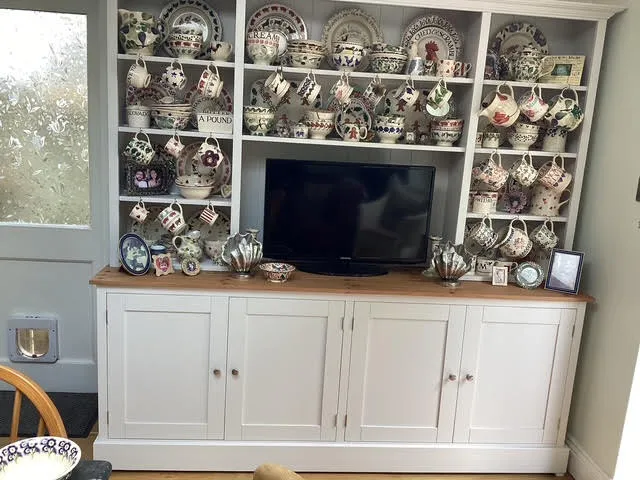 White painted dresser with open shelves of patterned pottery and an oak top