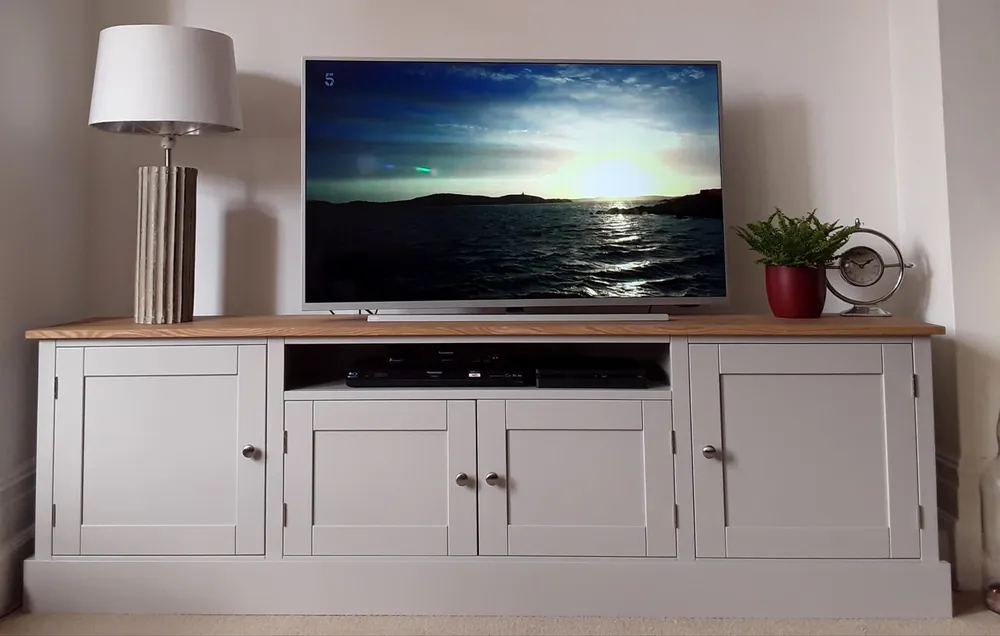 Grey painted TV cabinet with an oak top and cupboards either side of an open shelf